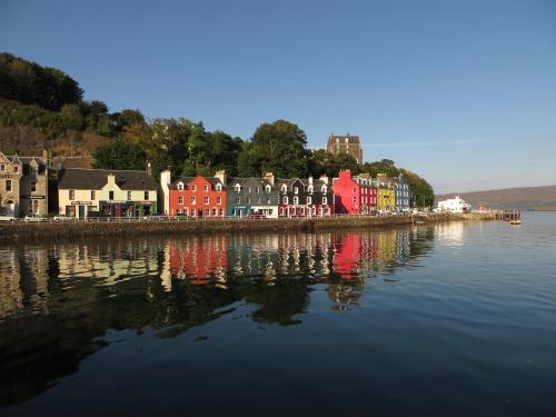 a group of houses on the shore of a body of water at Little Fox Lodge Luxury Hideaway with Hot Tub Glencoe Near Fortwilliam in Glencoe
