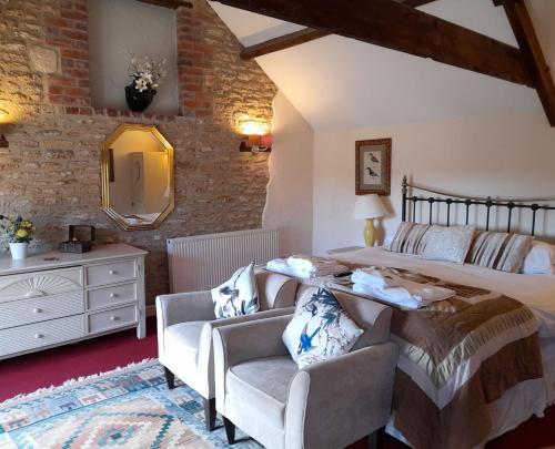 a bedroom with a bed and two chairs at Knoll Hill Farm, The Place To Stay in Frome