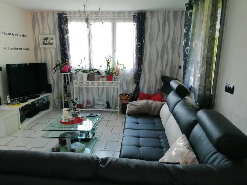 sala de estar con sofá de cuero negro en Maison de campagne à Balaives et Butz, en Flize