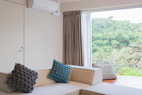 a living room with a couch and a large window at HOTEL PETIT SUITE SOGENJI ISHIMON in Naha