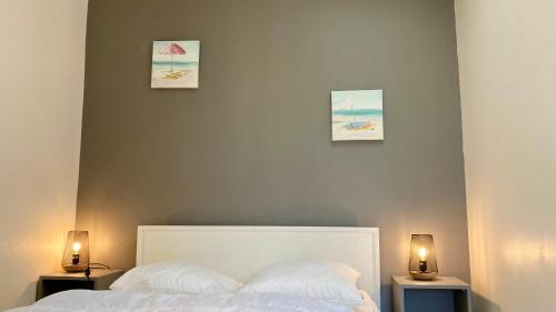 ein Schlafzimmer mit einem weißen Bett mit drei Bildern an der Wand in der Unterkunft La Tranquille - Maison pour 3 familles in La Michelière