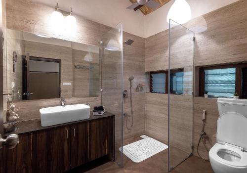 La salle de bains est pourvue d'un lavabo et d'une douche en verre. dans l'établissement SaffronStays Meadowbrook, Panvel - pet-friendly villa near Karnala Bird Sanctuary, à Āpta