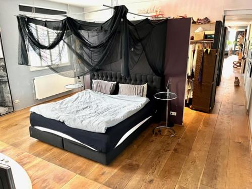 1 dormitorio con cama negra con dosel en Elegant penthouse LOFT of 250 m2 in city centre with huge roofgarden 80 m2, en Ámsterdam