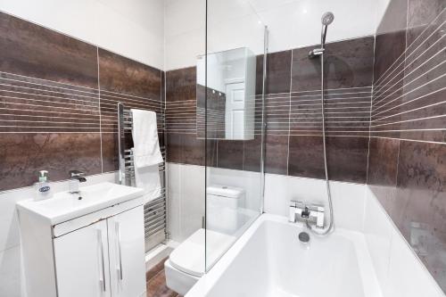 uma casa de banho com uma banheira, um lavatório e um chuveiro em Modern apartment close to city centre with parking em Leeds