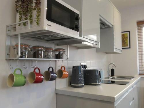 una cocina con tazas colgadas en la pared en The Middlewood - Luxury self contained retreat, en Adlington