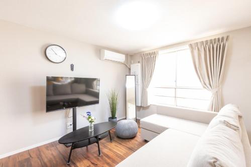 ein Wohnzimmer mit einem weißen Sofa und einem Tisch in der Unterkunft アリタ日本橋西3F in Osaka