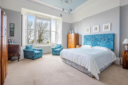 - une chambre avec un lit et deux chaises bleues dans l'établissement Stunning Apartment in Victorian Villa with Garden, à Torquay