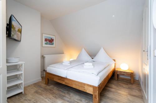 ein kleines Schlafzimmer mit einem Bett mit weißen Laken in der Unterkunft Süderliebe in Westerland