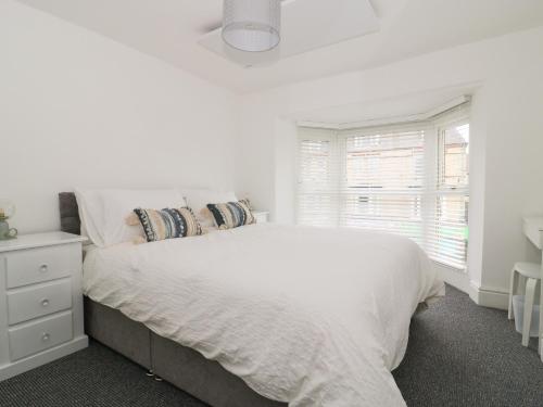 a white bedroom with a white bed and a window at Wave and Sea in Bridlington