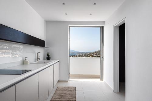 a kitchen with white counters and a large window at Black Stone Villa in Sounio