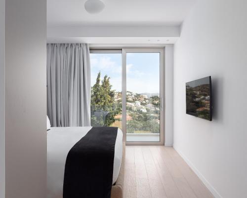 a bedroom with a bed and a large window at Black Stone Villa in Sounio