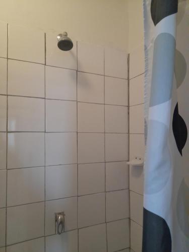 a bathroom with a shower with a white tiled wall at Sunset Guesthouse - Mthatha in Mthatha