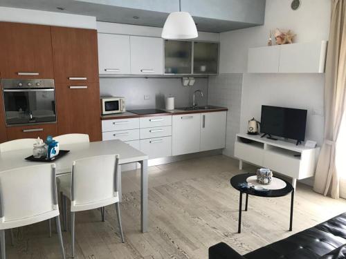 uma cozinha com armários brancos e uma mesa e cadeiras em CASA Chloe' em Lido di Jesolo