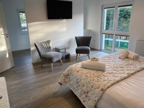 um quarto com uma cama e 2 cadeiras e uma televisão de ecrã plano em Remarkable 4-Bed House in St Minver Rock em Wadebridge