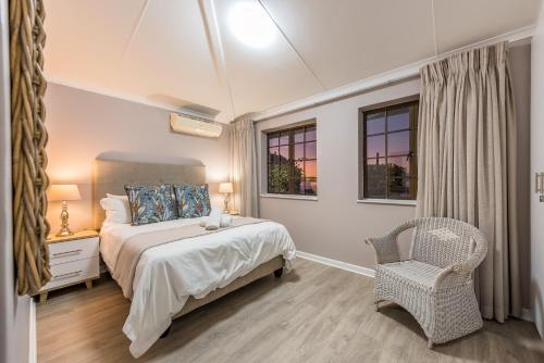 una camera con letto, sedia e finestre di Beacon Wharf , George Hay 1 Holiday Accommodation a Mossel Bay
