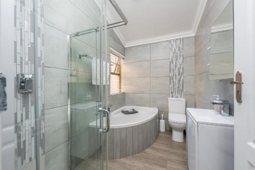 een badkamer met een douche, een toilet en een wastafel bij Beacon Wharf , George Hay 1 Holiday Accommodation in Mosselbaai
