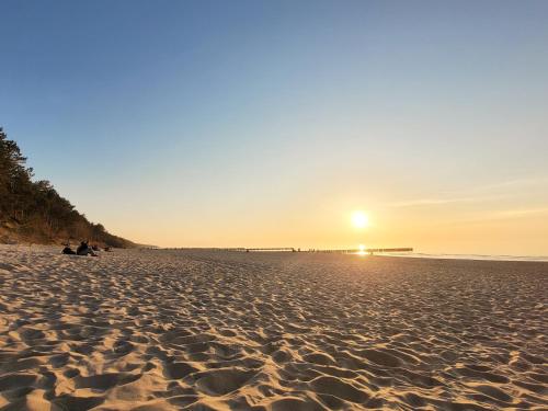 a beach with the sun setting over the ocean at Pine Point Apartament with terrace, shared pool, tennis court in Pobierowo