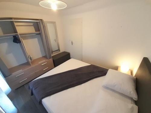 une petite chambre avec un lit et un miroir dans l'établissement Appartement Village Naturiste Lagon, au Cap d'Agde