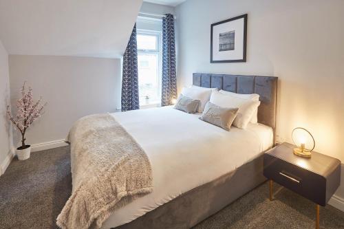 a bedroom with a large white bed with blue curtains at Host & Stay - King's Cottage in Amble