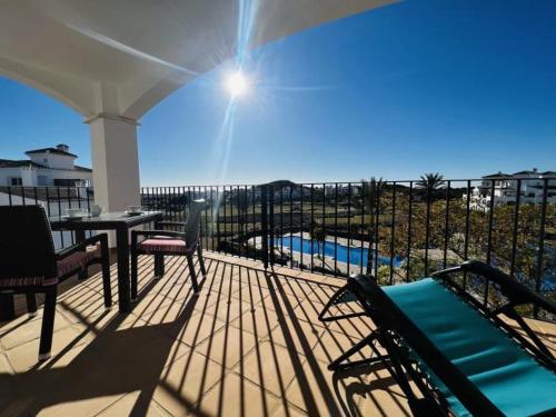 a balcony with chairs and a table and a pool at Golf and Relax, Modern 2 bedroom appartement Haciënda Riquelme Golf Atlantico in Sucina
