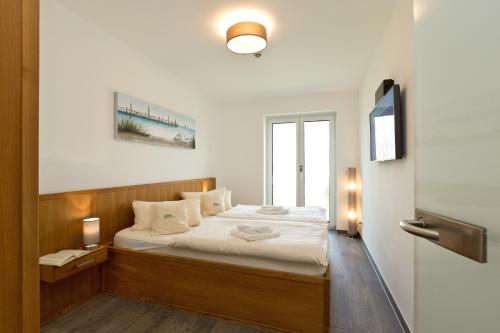 a bedroom with a bed with white sheets and a window at Kells Appartements in Klink