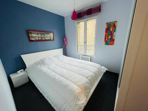 une chambre avec un lit blanc avec un mur bleu dans l'établissement belle brise, à Cancale