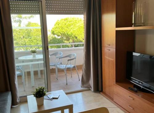 a living room with a television and a balcony with a table at Aparthotel Marsol in Castelldefels