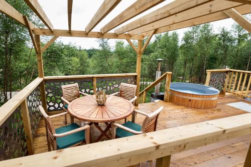 a wooden deck with a table and chairs and a hot tub at Yurtshire Eavestone Lake - Birch Yurt in Ripon