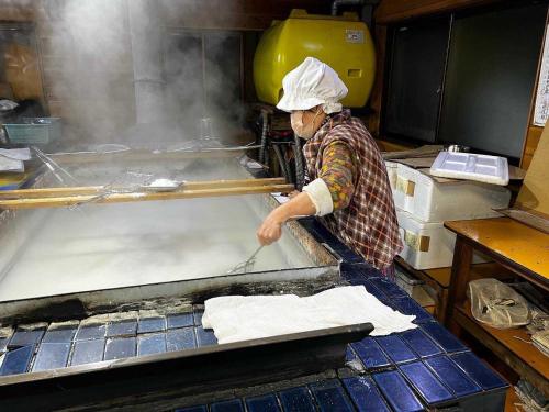 a person in a kitchen making food on a table at AWA Nishi-Izu in Numazu