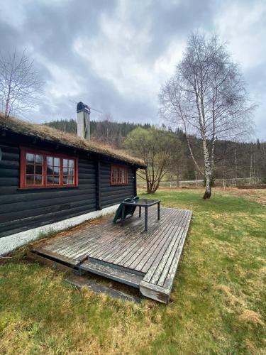 a picnic table on a wooden deck in front of a cabin at Morgedal Camping in Morgedal