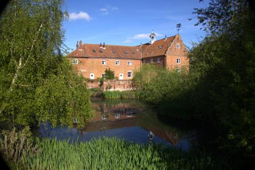 ein großes Backsteingebäude neben einem Fluss mit Bäumen in der Unterkunft Spixworth Hall Cottages in Spixworth