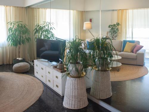 Nina's cozy apartment in Mikrolimano في بيرايوس: غرفة معيشة مع مزهريتين مع نباتات فيها