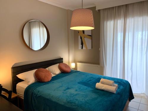 1 dormitorio con cama azul con almohadas y espejo en Agustin Apartment inThessaloniki -penthouse en Tesalónica