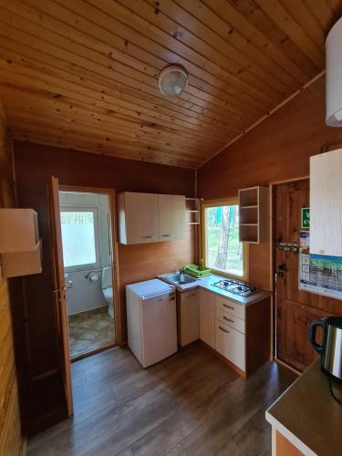 a kitchen with white appliances and a wooden ceiling at Leśna Przystań in Pobierowo