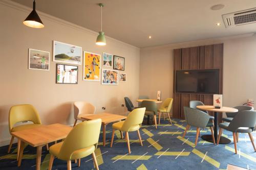 a waiting room with tables and chairs and a flat screen tv at Holiday Inn Basildon by IHG in Basildon