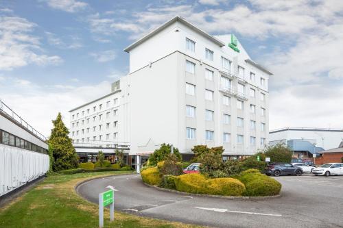 a white building with a parking lot in front of it at Holiday Inn Basildon by IHG in Basildon