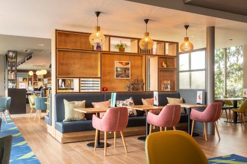 a restaurant with tables and chairs and lights at Holiday Inn Basildon by IHG in Basildon