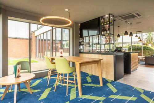 a bar with a wooden table and yellow chairs at Holiday Inn Basildon by IHG in Basildon