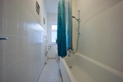 a bathroom with a tub and a shower with a blue shower curtain at HejU - Parking - Kitchen - Netflix - Kingsize Bett in Lübeck