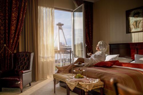 فندق دوفين في براتيسلافا: امرأة جالسة على سرير في غرفة فندق