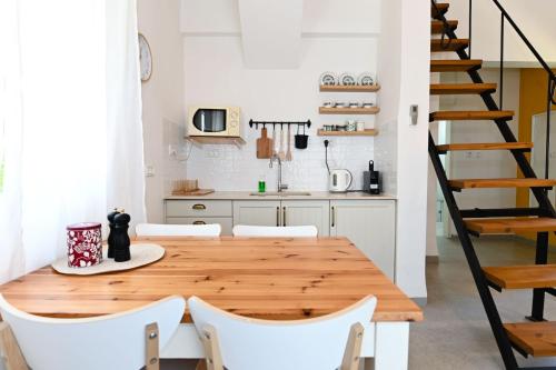 a kitchen with a wooden table and white chairs at YalaRent Valley view Boutique cottages with Pool in Merhavyāh