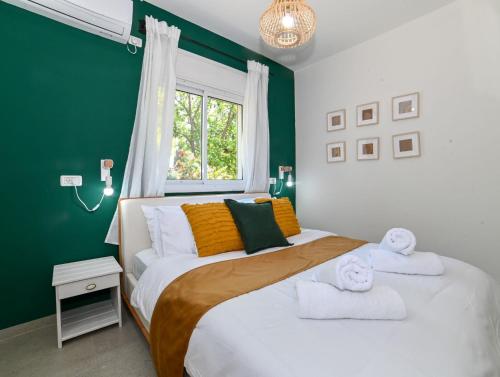 um quarto verde e branco com 2 camas e uma janela em YalaRent Valley view Boutique cottages with Pool em Merhavyāh