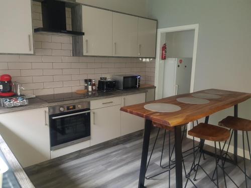 a kitchen with a wooden table with stools in it at Highfields Living - All Rooms Ensuite- Free Wifi- Free Local Parking in Sheffield