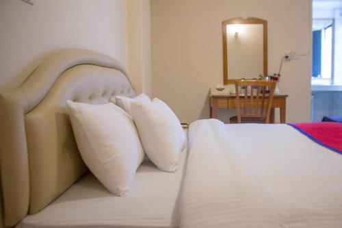 a bedroom with a bed with white pillows at Hotel The Enchanted in Dhaka