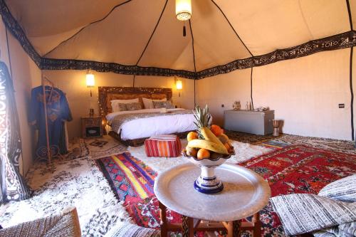 pokój z łóżkiem i stołem w namiocie w obiekcie Luxury traditional Tent Camp w mieście Merzouga