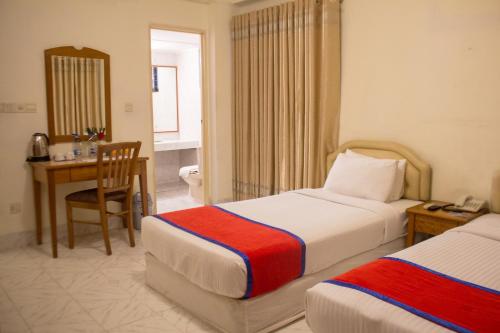 a hotel room with two beds and a desk at Hotel The Enchanted in Dhaka