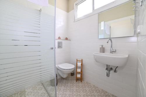 a white bathroom with a toilet and a sink at YalaRent Valley view Boutique cottages with Pool in Merhavyāh