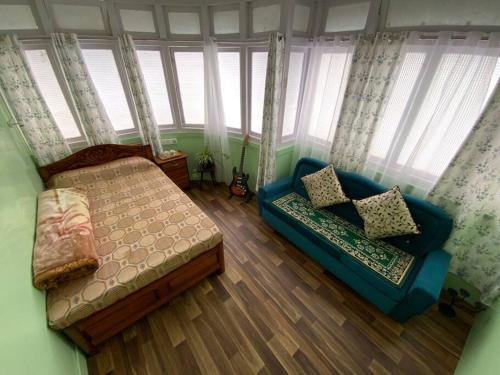 sypialnia z łóżkiem, kanapą i oknami w obiekcie Basnet Apartment w mieście Dardżyling