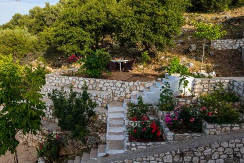 a garden with a stone wall and flowers at MAKRIS HOUSE in Ayia Evfimia