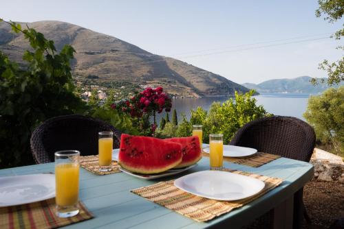 a table with a bowl of watermelon and glasses of orange juice at MAKRIS HOUSE in Ayia Evfimia
